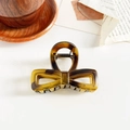 Detail view of a tortoiseshell bow hair claw clip on a stylish wooden background tray - 8cm Hollow Bowknot / Matte Tortoiseshell