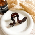 Close-up of S-shaped tortoiseshell hair claw clip with glossy resin and metal spring - 8cm / Glossy Amber
