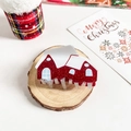 Detailansicht einer roten Glitzer-Haarklammer in Hausform für Weihnachten auf Holz - Schneehaus-Design