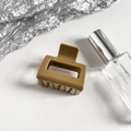 Detail of a square khaki hair claw clip on silver foil with a glossy resin finish - Turmeric