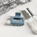 Close-up of a matte dusty blue rectangular hollow hair claw clip on a white surface - Light Blue