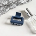 Detail view of navy blue square claw clip with hollow design on silver foil background - Sapphire Blue