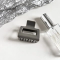 Macro detail of the grey hollow rectangular hair claw clip with smooth polished finish - Gray