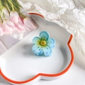 Detail view of a translucent blue plumeria hair claw clip on a decorative floral tray - Five-Petal Flower / 4cm / Gradient Sky Blue