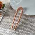 Nahaufnahme der Morandi-rosa U-Haarnadel für Dutt auf weichem beige Strickhintergrund - 11.5cm U-Form Haarstab / Glänzendes Orangepink