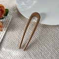 Macro shot of an elegant amber U-shaped hair pin on a white ceramic plate with a rose - Glossy Milk Coffee