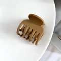 Detailed close-up of matte caramel brown seven-tooth hair claw clip for hair styling - Turmeric