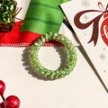 Macro view of green spiral hair tie with Christmas motifs and festive decorations - Green