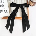 Detail of the elegant black velvet bow hair clip with long ribbons on a decor tray - Black