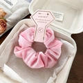 Close-up of pink velvet scrunchie displayed in gift packaging with branded card - Pink