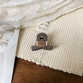 Gros plan d'une pince à cheveux rugby marron mat sur un tissu texturé de qualité - Pince à Cheveux Croisée Marron Foncé 4cm