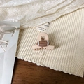 Détail d'une pince à cheveux rugby beige mate sur un tissu en tricot crème doux - Pince à Cheveux Croisée Nude 4cm