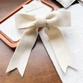 Detailopname van de crèmegebreide haarstrik met lange linten en zachte textuurafwerking - Beige