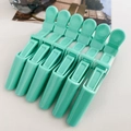 Close-up of six mint green alligator hair clips for professional styling and sectioning - Mint Green