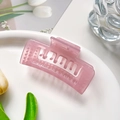 Detailopname van een semi-transparante roze rechthoekige haarklem in een stijlvolle setting - Gelei Roze