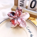 Detailed macro shot of marble textured floral hair claw clip on decorative ceramic tray - 8cm UV Printed Plumeria - ABS Beige Style K