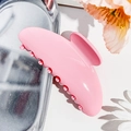Detailed close-up of glossy pink resin hair claw clip on silver metal tray with floral accents - Korean Pink