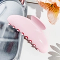 Close-up of pink matte hair claw clip on silver tray with decorative floral accent - Girl Pink