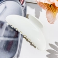 Detail of elegant white resin hair claw clip with white bead accents on metallic tray - Off White