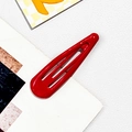 Detailed view of a glossy red metal drop hair clip with a polished lacquered finish - Alloy / Red