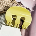 Dettaglio di una grande pinza per capelli giallo acceso con denti a onda sulla paglia - Verde Frutta