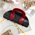 Detail view of a black and wine red contrast hair claw clip on a stylish display board - Semicircle Bag - Black