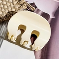 Vista dettagliata della grande clip per capelli in resina avorio su uno sfondo elegante - Beige