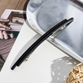 Dettaglio di una molletta nera opaca minimalista su un vassoio metallico con luce naturale - Doppia Barra da 13 cm / Nero opaco