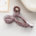 Detail of a purple marble acetate bow hair claw clip with a strong golden metal spring - Brown