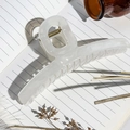 Close-up of a large white jelly resin hair claw clip on a notebook with floral accents - Off White