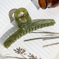 Detail view of a large translucent green hair claw clip on a notebook with vintage props - Dark Green