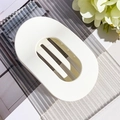 Detail view of large matte white oval hair claw clip with strong grip on glass tray - Matte Cream