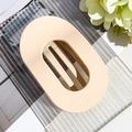 Close-up of matte nude pink oval hollow hair claw clip with strong grip on textured glass - Matte Light Coffee