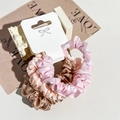 Close-up of three satin scrunchies in pink and champagne colors on a white product card - Light Pink/Light Green/Pink