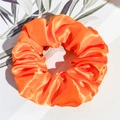 Nahaufnahme des leuchtend orangen Satin-Haargummis mit seidiger Textur und Falten - Neon Satin - Hellorange