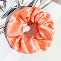 Detail eines korallenorangen Satin-Haargummis mit glänzendem Seideneffekt und Falten - Neon Satin - Orangepink