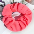 Gros plan d'un grand chouchou rose en satin avec texture douce et ombres de feuilles - Chiffon Néon - Rose Orangé
