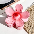 Detail shot of a large pink gradient flower hair claw clip on a textured fabric surface - Plastic/Resin / Pink Gradient