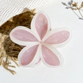 Detailed top view of a peach and white plumeria flower hair claw clip on neutral textures - Pink and Beige