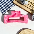 Macro shot of large pink marble hair claw clip with rectangular cutout on fabric - Dark Pink Marble