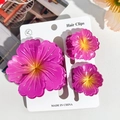 Detail of three purple plumeria hair clips in large and small sizes on card - Hibiscus Triple Clip Set - Gradient Rose Red
