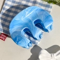 Dettaglio della texture marmorizzata blu e bianca su una molletta per capelli in resina - Celeste
