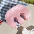 Vue macro d'une grande pince à cheveux rose à texture marbrée sur un tissu à carreaux - Rose