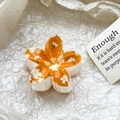 Macro detail of orange plumeria hair claw clip with floral patterns on white paper - Orange Daisy Style (103-5)