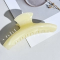 Macro view of cream-colored marble textured hair claw clip on minimalist background - Light Orange