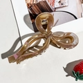 Macro detail of large amber marble acetate bow claw clip with gold metal spring mechanism - Coffee Bow Style