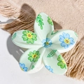 Close-up of a pale green plumeria hair claw clip with printed floral patterns on linen - Pale Green Blue Green Daisy Style / ABS