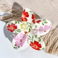Macro shot of white flower hair claw with colorful floral UV print on beige fabric - Creamy White Red Pink Yellow Flower Style / ABS