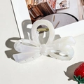 Close-up of pearl white bow hair claw clip with iridescent finish and gold spring - Beige Small Bow Style