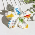 Detail showing white flower hair claw clip with colorful cartoon dinosaur prints - White Dinosaur Illustration Print (139-4)